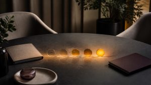 Premium editorial meeting table with two notebooks and a progression of illuminated glass signal tokens